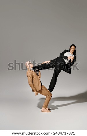 young businesswoman using smartphone and balancing with help of acrobat man in suit in studio