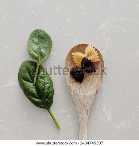a spoon with pasta and a leaf Royalty-Free Stock Photo #2434745507