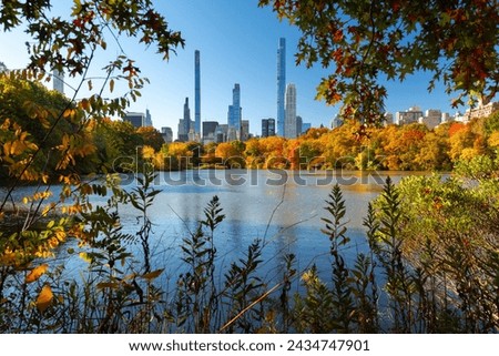 Central Park and the vivid colors of autumn by the Lake with view of Billionaires' Row skyscrapers. Manhattan, New York City