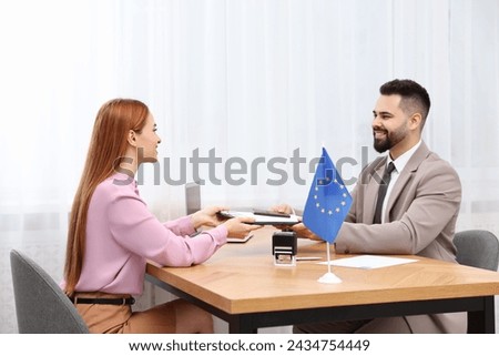 Immigration to European Union. Woman giving visa application form to embassy worker in office Royalty-Free Stock Photo #2434754449