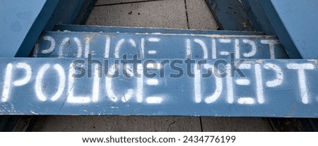 police dept (department) sign on blue wooden barricade laid on cement pavement sidewalk (painted stencil lettering) Royalty-Free Stock Photo #2434776199