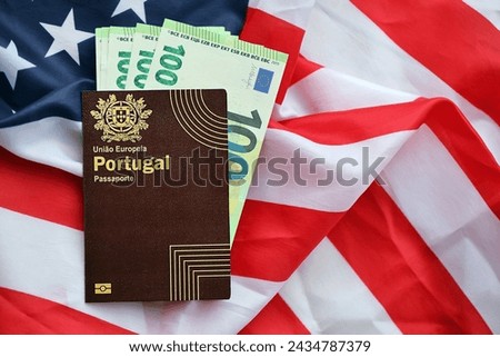 Red Portugal passport of European Union and money on United States national flag background close up. Tourism and diplomacy concept