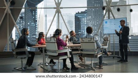 Modern South Asian Business Office Meeting: Confident Indian Manager Uses Interactive Display, Makes Report to a Group of Corporate Partners, Shows Statistics, Growth and Financial Analytics Royalty-Free Stock Photo #2434800147