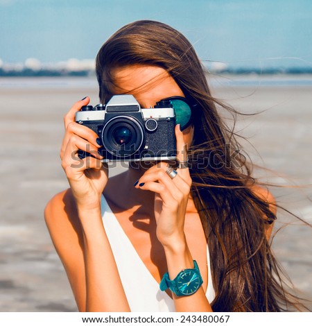 Close up Portrait of beautiful  woman with retro hipster camera having fun at the beach , wearing blue sunglasses and watch .