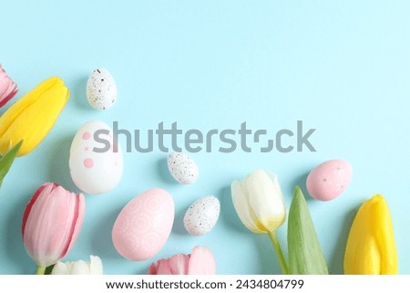 Easter decor concept. Top view photo of colorful eggs with tulip flowers on color background
