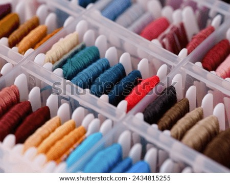 Bobbins with different colour embroidery threads in a plastic sorting box. Close-up Royalty-Free Stock Photo #2434815255