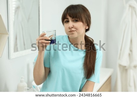 Young woman using mouthwash in bathroom. Oral hygiene Royalty-Free Stock Photo #2434816665