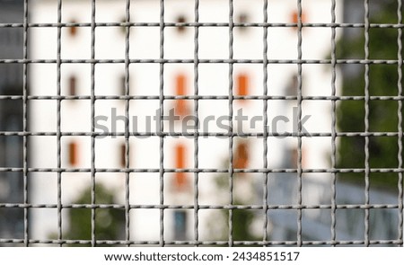 metal fence separating the border and the building intentionally blurred in background Royalty-Free Stock Photo #2434851517
