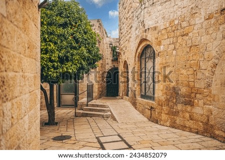 Cozy narrow small Street in the Old City of Jerusalem, Israel. Typical stoned houses and walls of jewish historic quarter area part. Royalty-Free Stock Photo #2434852079