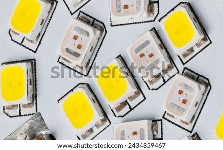 Closeup of light-emitting diodes on electronic LED circuit inside a household lamp. Electric light sources of yellow and white color temperature on printed wiring board detail. Surface mount assembly.