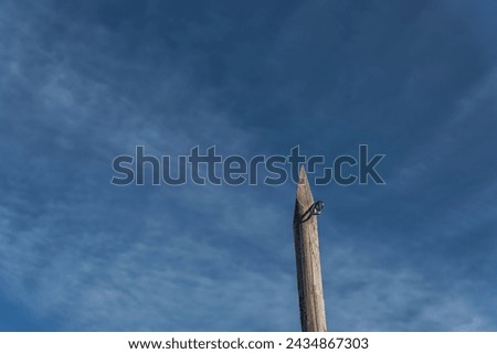 wooden pointed pole with metal lock stands out against a slightly cloudy blue sky