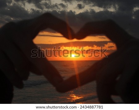Hand heart around beautiful sunset