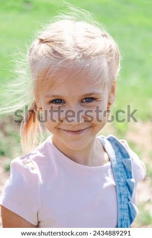 A joyful young girl smiles outdoors, embodying childhood happiness, healthy living, and the vitality of nature in her sunny, grassy backdrop. High quality photo