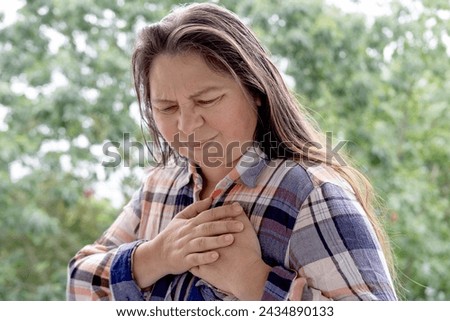 woman 40-45 years old in plaid shirt holds to heart, sudden chest pain, close up female face with facial expression suffering, Ischemic heart disease, Arterial hypertension, Myocarditis or Arrhythmia Royalty-Free Stock Photo #2434890133