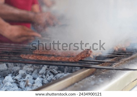 Adana kebabs are grilling on a barbecue with smoke, close up, outdoor photography 