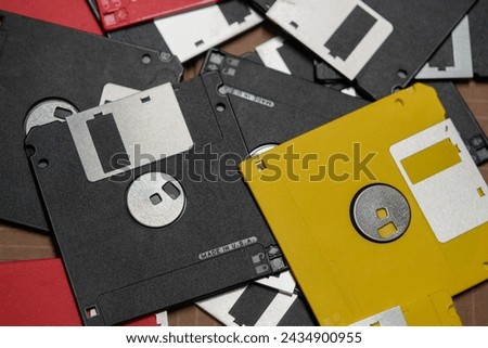 Looking down at black, yellow, and red floppy drives in a cardboard box. 