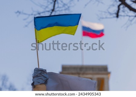 Russian and ukraine flags on a display in front of russian embassy in Berlin. Concept of one country against each other, banners representing sides. Flag of ukraine in front of Russia on a sunny day.