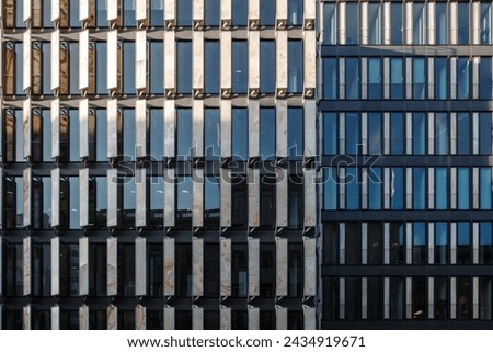 The geometric symmetry of modern office building facades with a mix of reflective glass windows and structured metal frames.