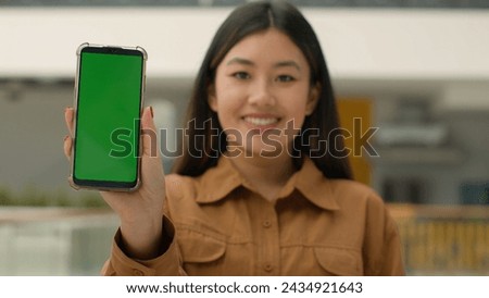 Mobile phone device focus blurred Asian business woman chinese girl hold smartphone green mock-up happy businesswoman advertise cellphone chroma key empty display web service cell gadget advertisement
