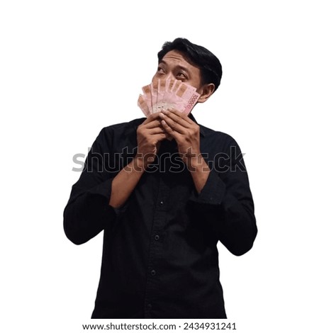 Portrait of a cheerful young asian man holding banknotes and looking at copy space isolated on white background