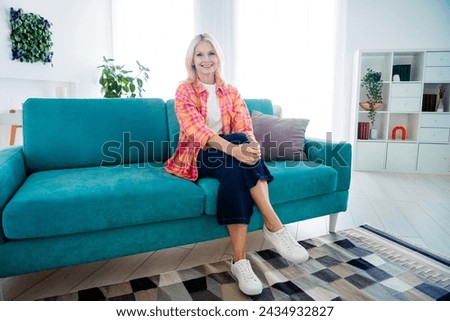 Photo of attractive cheerful old lady sit comfy divan looking recording blog about new rent house