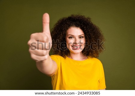 Photo of optimistic people concept young woman in yellow t shirt showing thumb up rate your results isolated on khaki color background