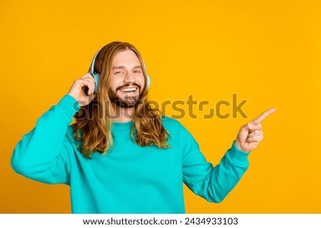 Photo of positive person arm touch headphones indicate finger empty space isolated on yellow color background