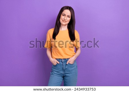 Photo of cheerful cool woman with straight hairstyle dressed orange t-shirt keep palms in pockets isolated on purple color background