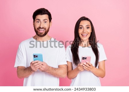 Photo portrait of lovely young couple hold devices shocked big sales dressed stylish white garment isolated on pink color background