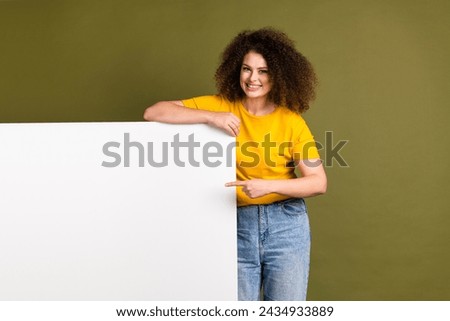 Photo of cheerful optimistic young woman in yellow t shirt direct finger touchscreen smartphone isolated on khaki color background