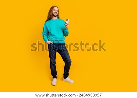 Full size photo of positive man put hand pocket hold smart phone empty space isolated on yellow color background