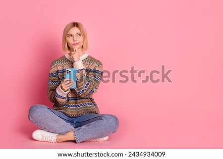 Full size photo of minded clever woman wear ornament pullover sit with smartphone look empty space isolated on pink color background