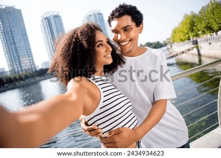 Photo of positive cute sweet couple cuddling making selfie recording video online live stream walk in town park sunny summer outside