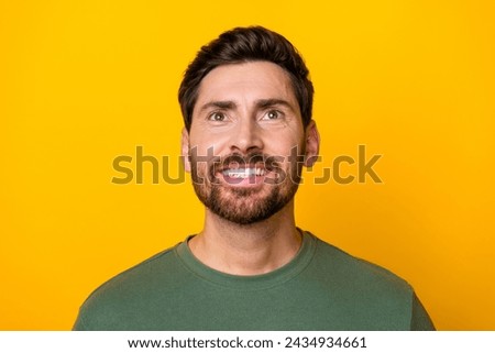 Photo of funky cheerful man wear khaki t-shirt smiling looking up empty space isolated yellow color background