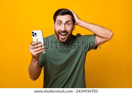 Photo portrait of attractive young man hold device excited impressed dressed stylish khaki clothes isolated on yellow color background