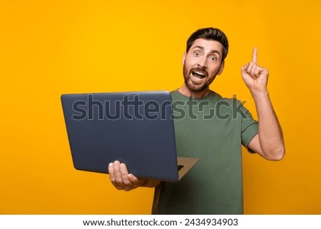 Photo portrait of attractive young man hold netbook point up eureka dressed stylish khaki clothes isolated on yellow color background
