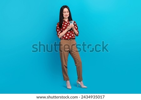 Full size photo of intelligent person wear red blouse brown trousers look at smartphone read email isolated on blue color background