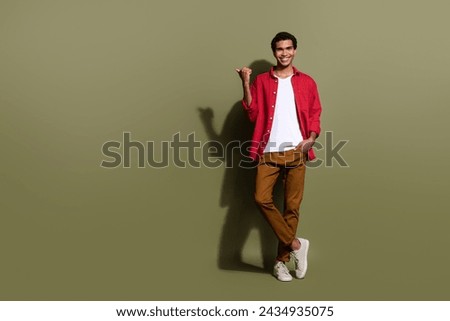 Full length photo of cool positive guy wear red shirt showing thumb empty space isolated khaki color background
