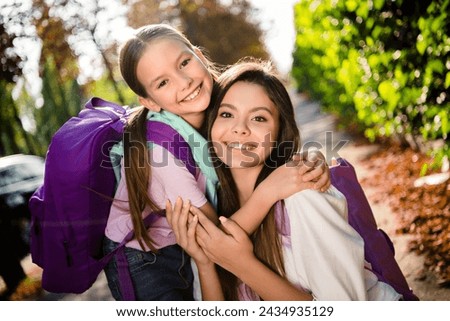 Photo of two lovey idyllic sisters toothy smile cuddle carry school bag warm sunny weather park outside Royalty-Free Stock Photo #2434935129