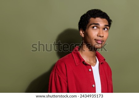 Photo of thoughtful positive guy wear red shirt looking back empty space isolated khaki color background