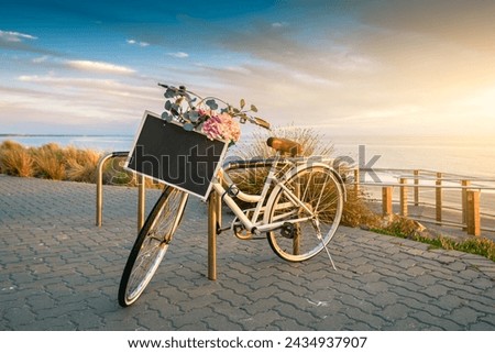 Vintage bicycle with text banner frame on a steering wheel parked near the beach at sunset time