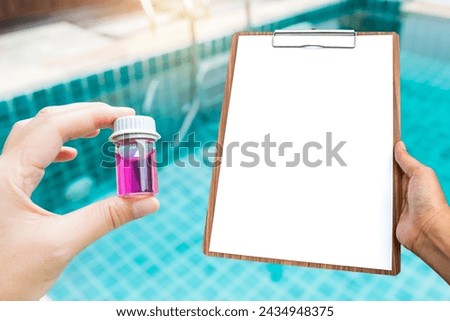 Glass vials and blank report paper on wooden clipboard in girl hand over blurred swimming pool background, outdoor day light, pH test