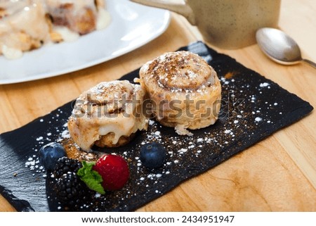 Picture of tasty baked cinnabon rolls served with powdered sugar and berries
