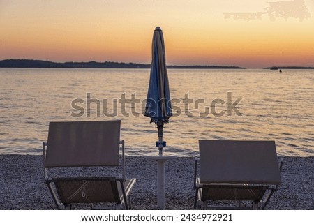 Picture of the sunset on the beach of the Croatian coastal town of Fazana with sun lounger and parasol in summer