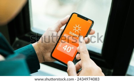  Hand holding smartphone with weather hot sunny day on screen and sunrise on midday at dry forest background. High Temperature Weather show on Mobile Screen on Hot Sunny Day. concept global warming Royalty-Free Stock Photo #2434974083