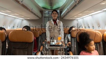 Air hostess or cabin crew working in airplane. Flight attendant pushing the cart on aisle for serving food and drink to passengers in airplane cabin. Airline transportation and tourism concept. Royalty-Free Stock Photo #2434976101