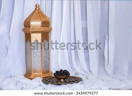 Big lantern with dates on a golden bowl isolated on white curtain background, Iftar food concept image