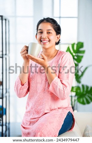 Indian pretty girl drinking coffee or tea from mug at home Royalty-Free Stock Photo #2434979447