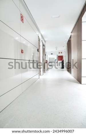 Bright and sterile hospital corridor with visible emergency signage.