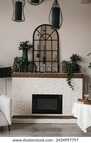 Fireplace with a mirror above it and a table with a vase and wine glasses on it